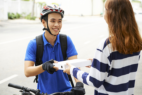 Smiling handsome young delivery man giving box of pizza to female customer
