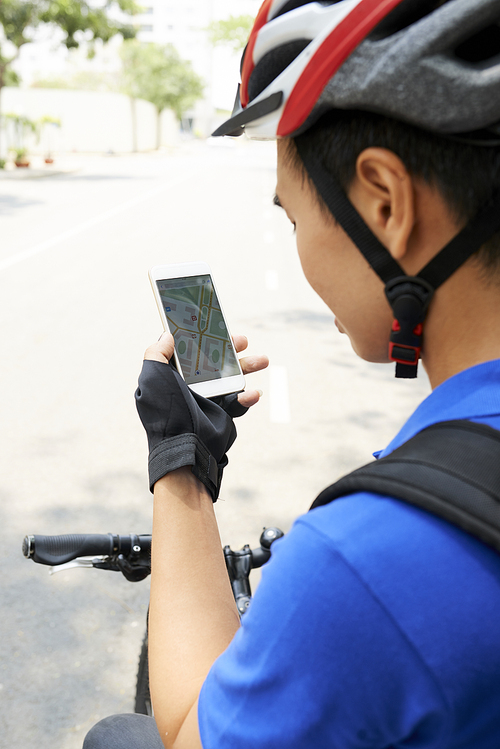 Delivery man in bicycle helmet checking map on smartphone screen