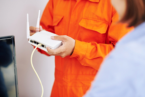 Close-up image of electrician explaining woman how to use wi-fi router he just installed