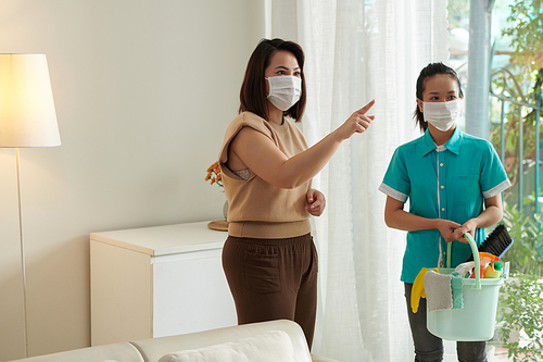 Owner in mask giving instruction to maid to disinfecting the room after coronavirus disease