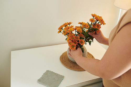 Close-up of young woman making bouquet from flowers in vase on table to decorate her room