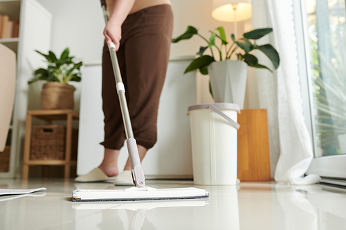 Close-up of housewife using mop to wash the floor in the room, she doing wet cleaning