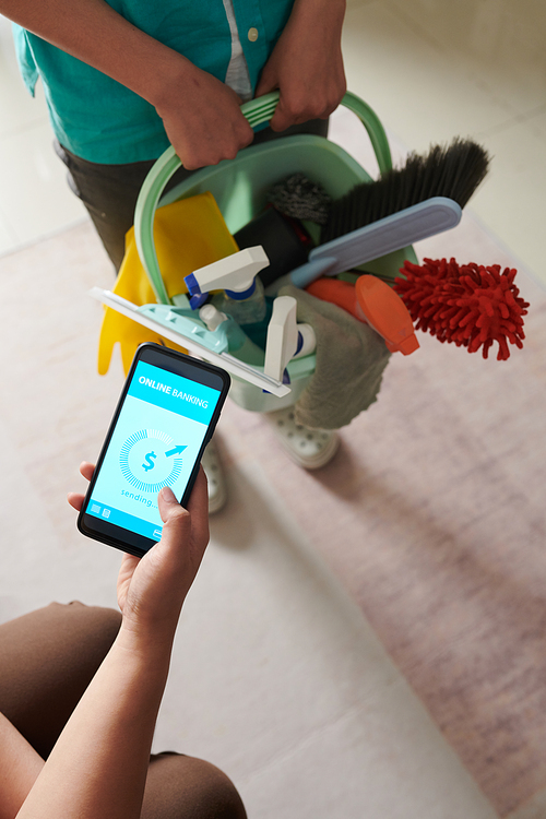 Close-up of customer paying for cleaning service online using her mobile phone