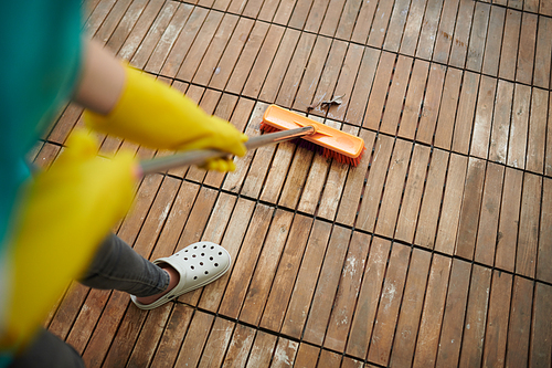 Close-up of janitor in protective gloves sweeping with mop outside of the house