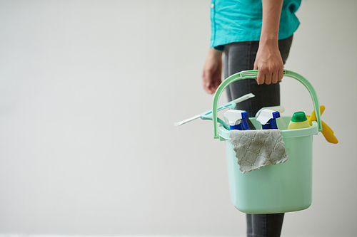 Close-up of cleaning worker holding bucket with detergents for house working isolated on white background