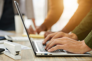 Hands of businessman working on laptop, filing forms and documents or answering e-mails