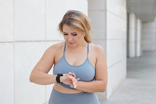 Pretty fit plus size woman checking her activity and ammount of burned calories via application on smartphone