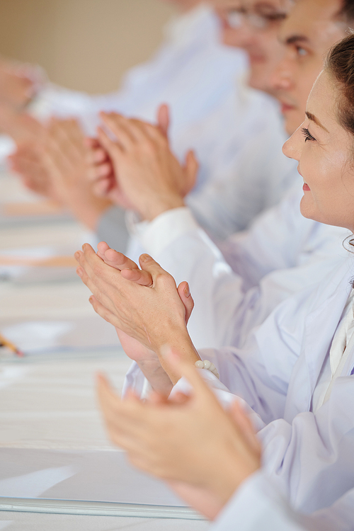 Close-up image of researchers applauding to speaker at medical conference