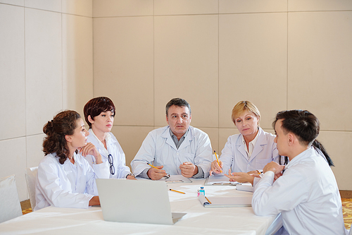 Group of serious researchers having emergency meeting and discussing side effects of new coronavirus vaccine