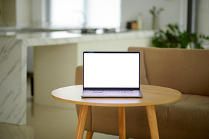 Opened laptop with empty screen on small coffee table