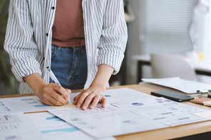 Businesswoman taking notes on stickers when working with reports and diagrams