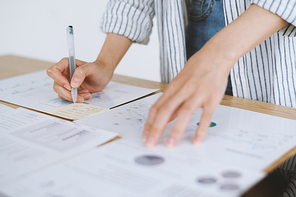 Closeup image of business lady analyzing reports and writing down main ideas