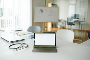 Tablet computer with empty screen on desk of doctor in hospital