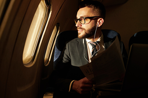Side view portrait of smiling young businessman looking in window enjoying sunset view from plane, copy space