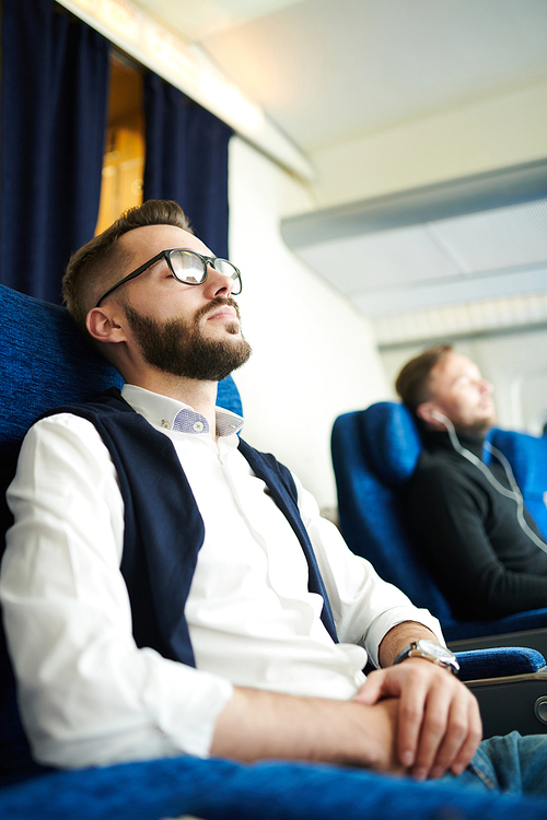 Side view portrait of handsome bearded man sleeping  while enjoying first class flight sitting in comfortable seat of modern plane, copy space