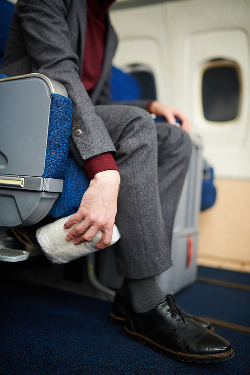 Portrait of unrecognizable man hiding bag of drugs under seat in plane dropping illegal substances, copy space