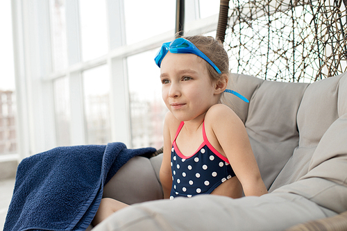 Positive content beautiful girl in swimsuit and giggles on head sitting in comfortable hanging chair with pillow and dreaming of future career in sport