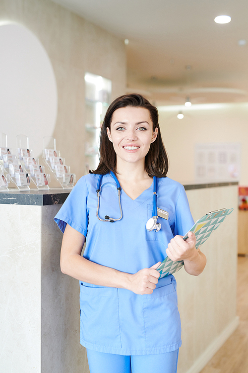 Portrait of  young female doctor  and smiling cheerfully while posing in hall of modern clinic