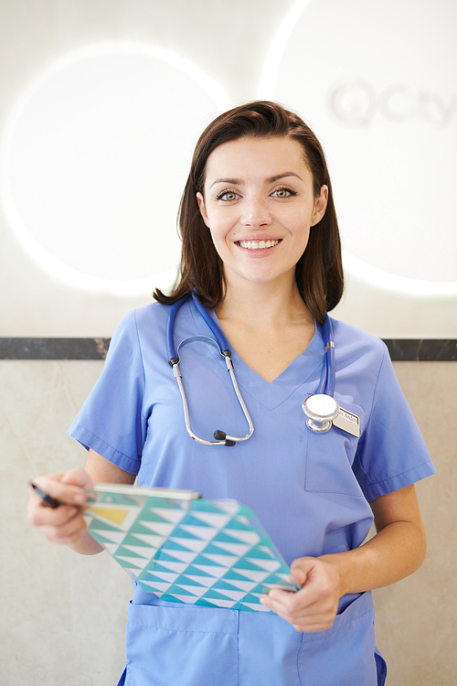 Portrait of smiling female medic  while posing in hall of modern clinic, copy space