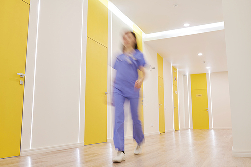 Wide angle view at corridor in modern clinic with blurred shape of nurse walking by, copy space