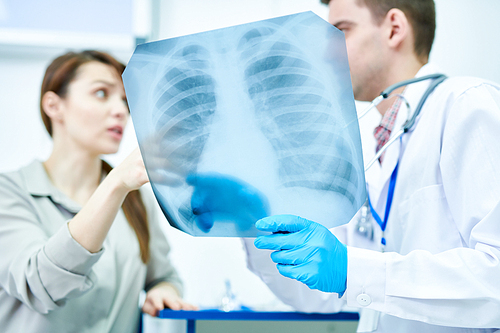 Waist up portrait of doctor holding chest x-ray explaining in to female patient, copy space