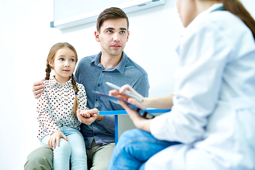 Crop view of dad holding daughter by hand at doctor appointment