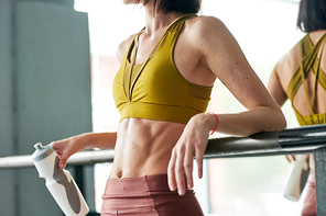 Mid section portrait of unrecognizable muscular woman relaxing after tough workout in gym, focus on abdomen