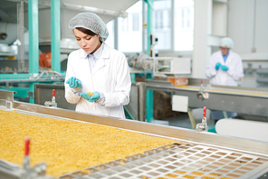 Portrait of pretty young woman working at modern food factory and  inspecting macaroni on production line, copy space