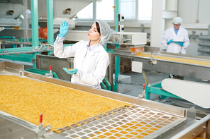 Portrait of young woman working at modern food factory and  inspecting macaroni on production line, copy space