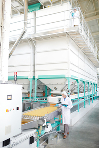 Wide angle portrait  of senior woman standing by conveyor belt at modern food factory, copy space
