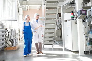 Full length portrait of young female worker giving tour of factory to senior woman, copy space