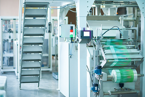 Interior of production workshop at food factory, modern machine units for packaging in focus, copy space