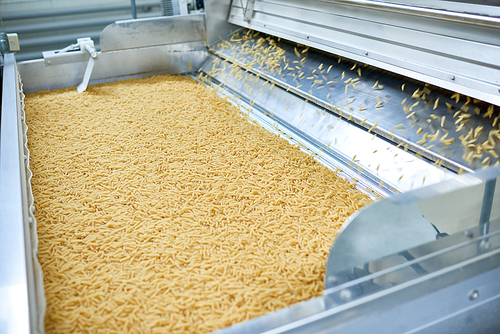 Crop shot  of dry macaroni spilling from machine unit on modern food production factory, copy space