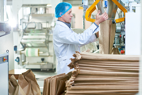 Side view portrait of senior factory worker in packaging section of modern production workshop, copy space