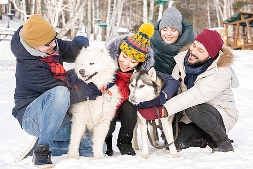 Full length portrait of two couples playing with two beautiful dogs outdoors in winter resort, copy space