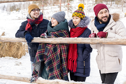 Waist up  portrait of four young people leaning on wooden fence enjoying winter vacation together