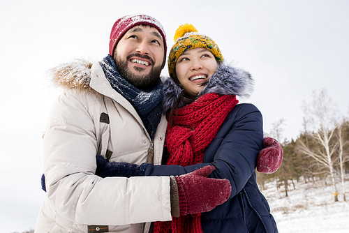 Portrait of young Asian couple embracing smiling happily enjoying nice winter days outdoors, copy space