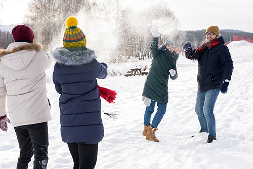 Portrait of two couples couple having fun in snow enjoying snowball fight during nice winter day outdoors on ski resort