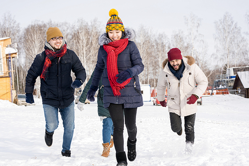 Portrait of four young people running towards camera having fun and enjoying nice winter days outdoors, copy space