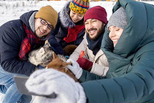 Portrait of two young couples taking selfie with dogs enjoying nice winter day outdoors