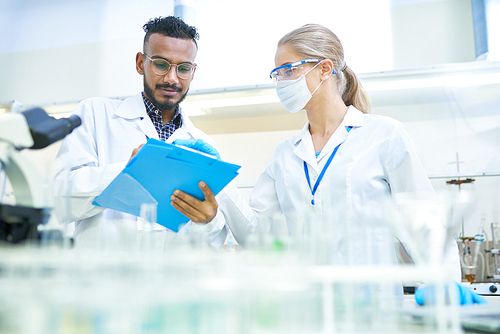 International team of scientists working together in medical laboratory doing research on  chemicals and bacteria