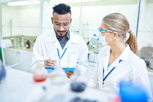 Portrait of international team of scientists working together in medical laboratory doing research on  chemicals and bacteria