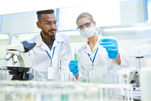 Portrait of young Middle-eastern scientist researching antibiotics while working on medical research in laboratory while his female colleague