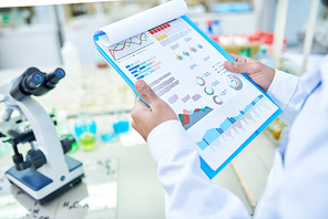 Close-up of unrecognizable laboratory worker viewing statistical data while analyzing result of DNA test