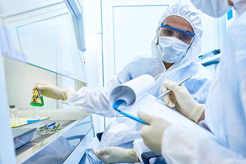 Portrait of two scientists wearing protective suits and masks working with hazardous materials in medical research laboratory