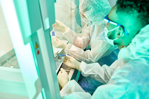 High Angle portrait of two unrecognizable scientists wearing protective suits  working with hazardous materials in medical research laboratory