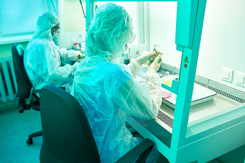 Back view portrait of two unrecognizable scientists wearing protective suits  working with hazardous materials in medical research laboratory