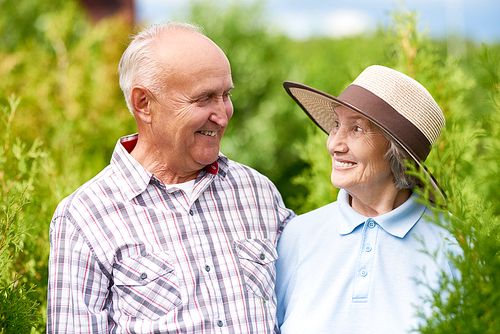 Portrait of happy senior couple posing embracing tenderly and looking at each other in beautiful garden