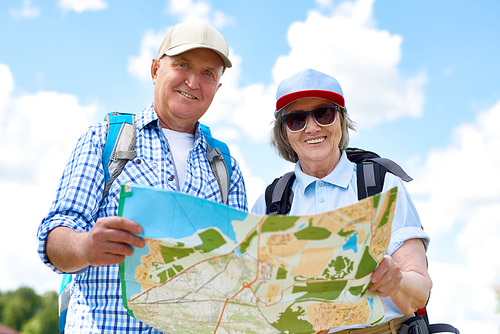 Portrait of active senior couple travelling on hiking trip, smiling  and  holding map together