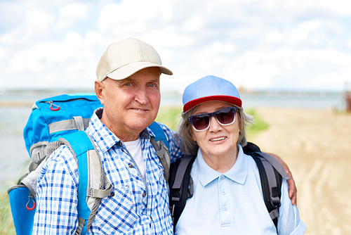 Waist up portrait of active senior couple travelling on hiking trip, smiling  enjoying vacation